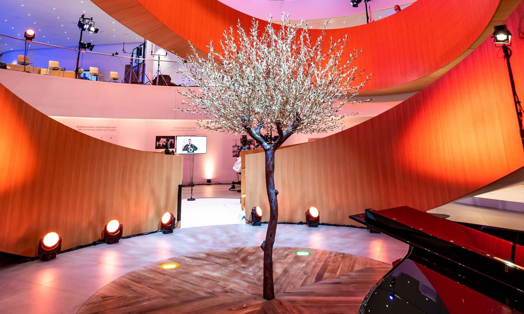 Einzelner Baum in einem orange beleuchteten Raum mit Klavier daneben